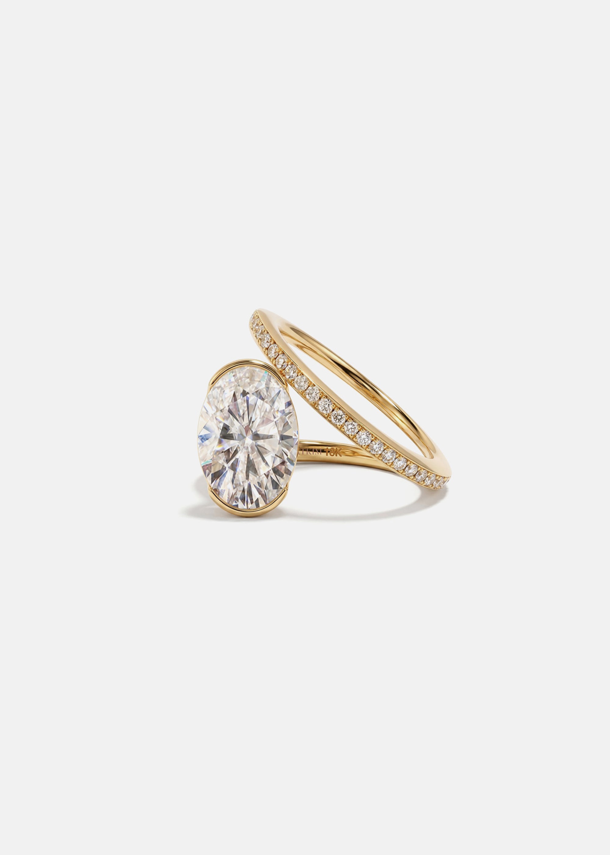 18k yellow gold bypass ring featuring a floating oval cut diamond and tapering micro-pavé band