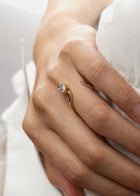 model wearing a 18k yellow gold open wrap ring featuring a pear-cut diamond and a pavé diamonds along the band.