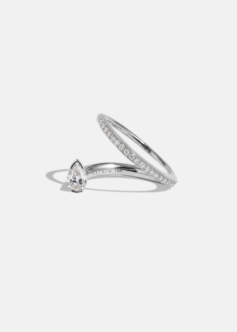 18k white gold engagement ring featuring a floating pear cut diamond on an architectural tilted micropavé band against a reflective surface.