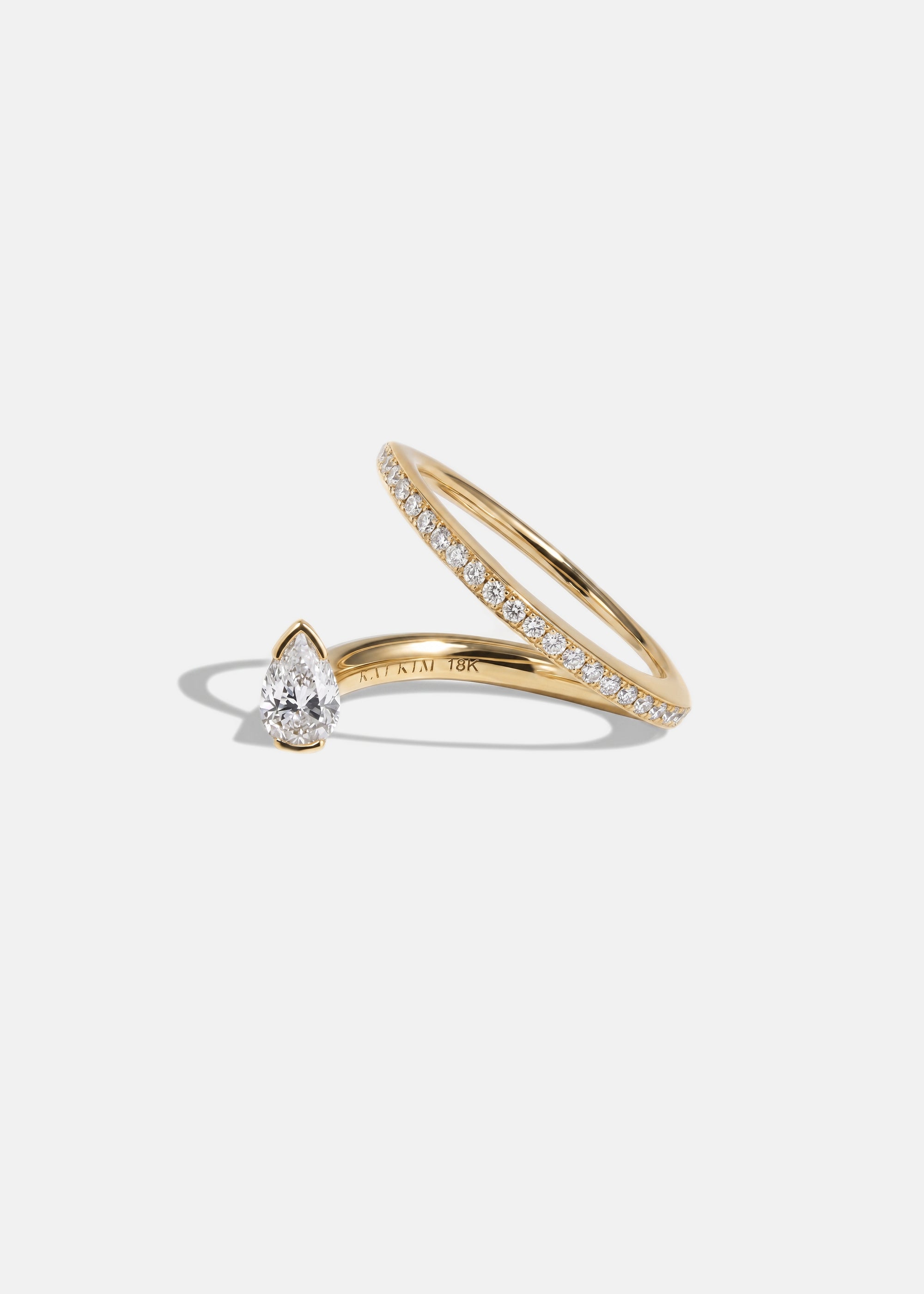 18k yellow gold engagement ring featuring a floating pear cut diamond on an architectural tilted micropavé band.