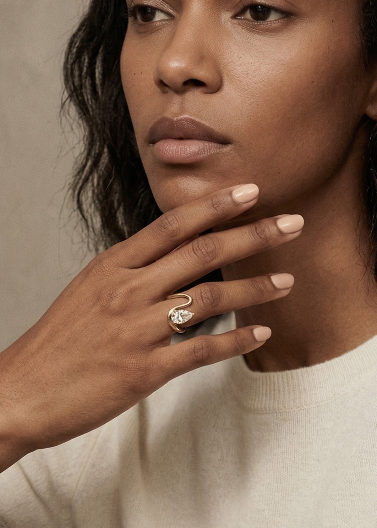 model wearing 18k yellow gold trace band with a floating pear cut diamond on ring finger