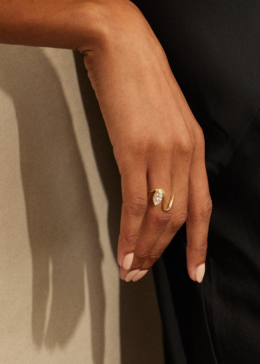model wearing 18k yellow gold trace band with a floating pear cut diamond on ring finger