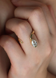 model wearing a 18k yellow gold open wrap ring featuring a pear-cut diamond and a pavé diamonds along the band.