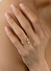 model wearing a 18k yellow gold open wrap ring featuring a pear-cut diamond and a pavé diamonds along the band.