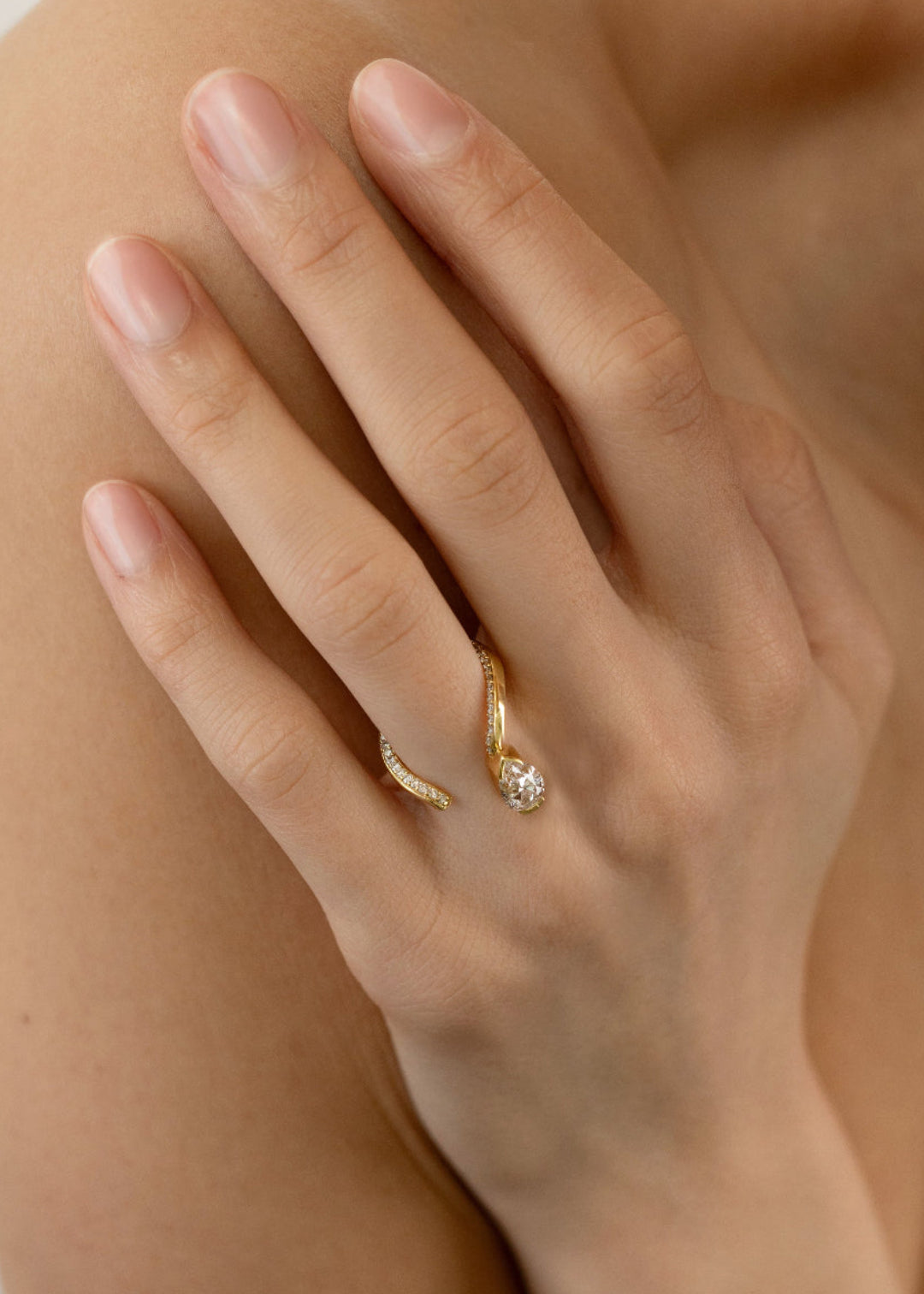 model wearing a 18k yellow gold open wrap ring featuring a pear-cut diamond and a pavé diamonds along the band.