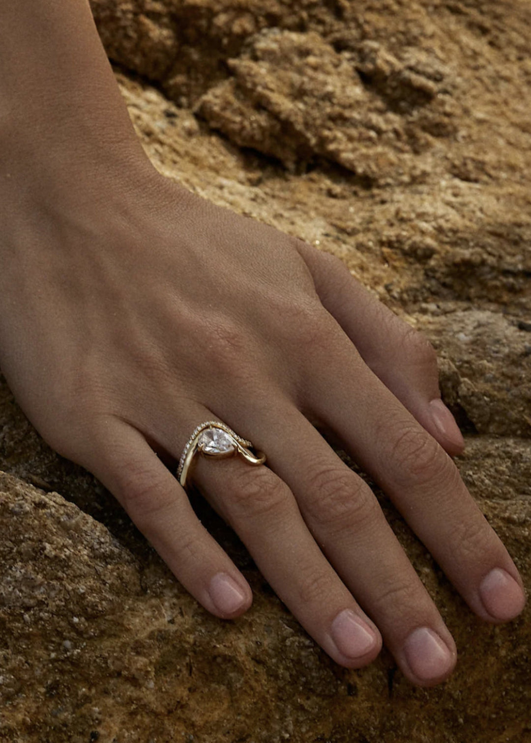 Model wearing a gold wave band with a pear cut diamond paired with a wave band of pavé diamonds -18K yellow gold-