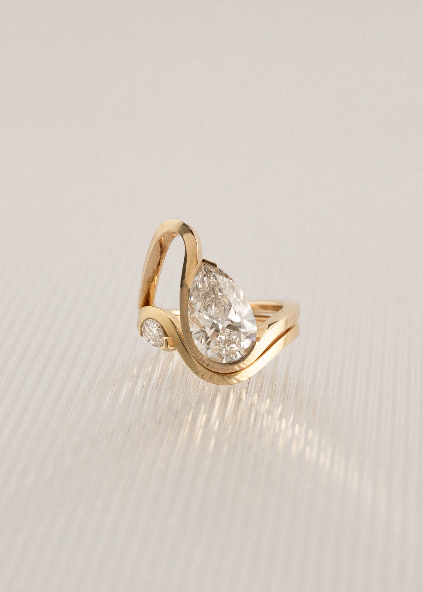 A gold wave band with a pear cut diamond paired a solid wave band with a small pear cut diamond-18K yellow gold