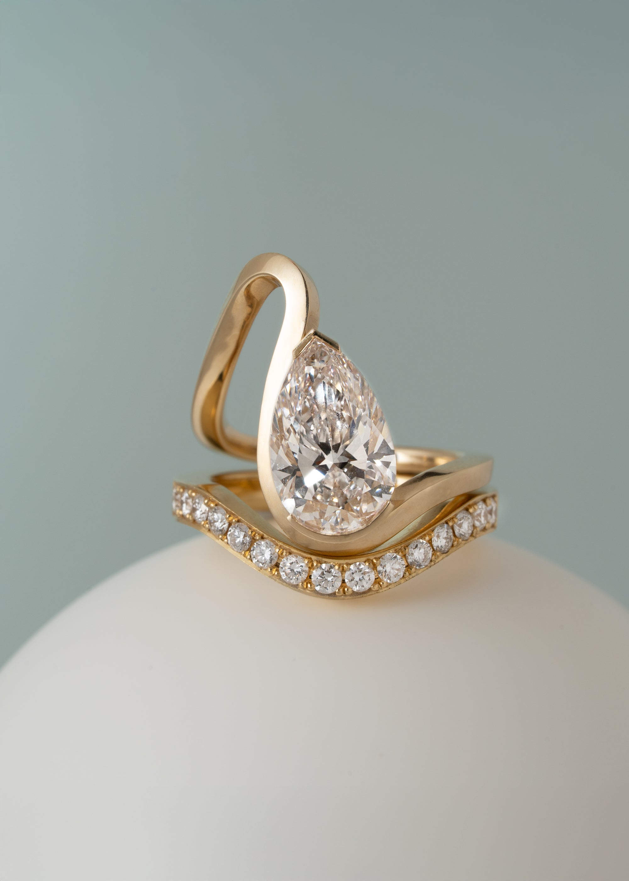 A gold wave band with a pear cut diamond paired with a wave band of pavé diamonds-18K yellow gold