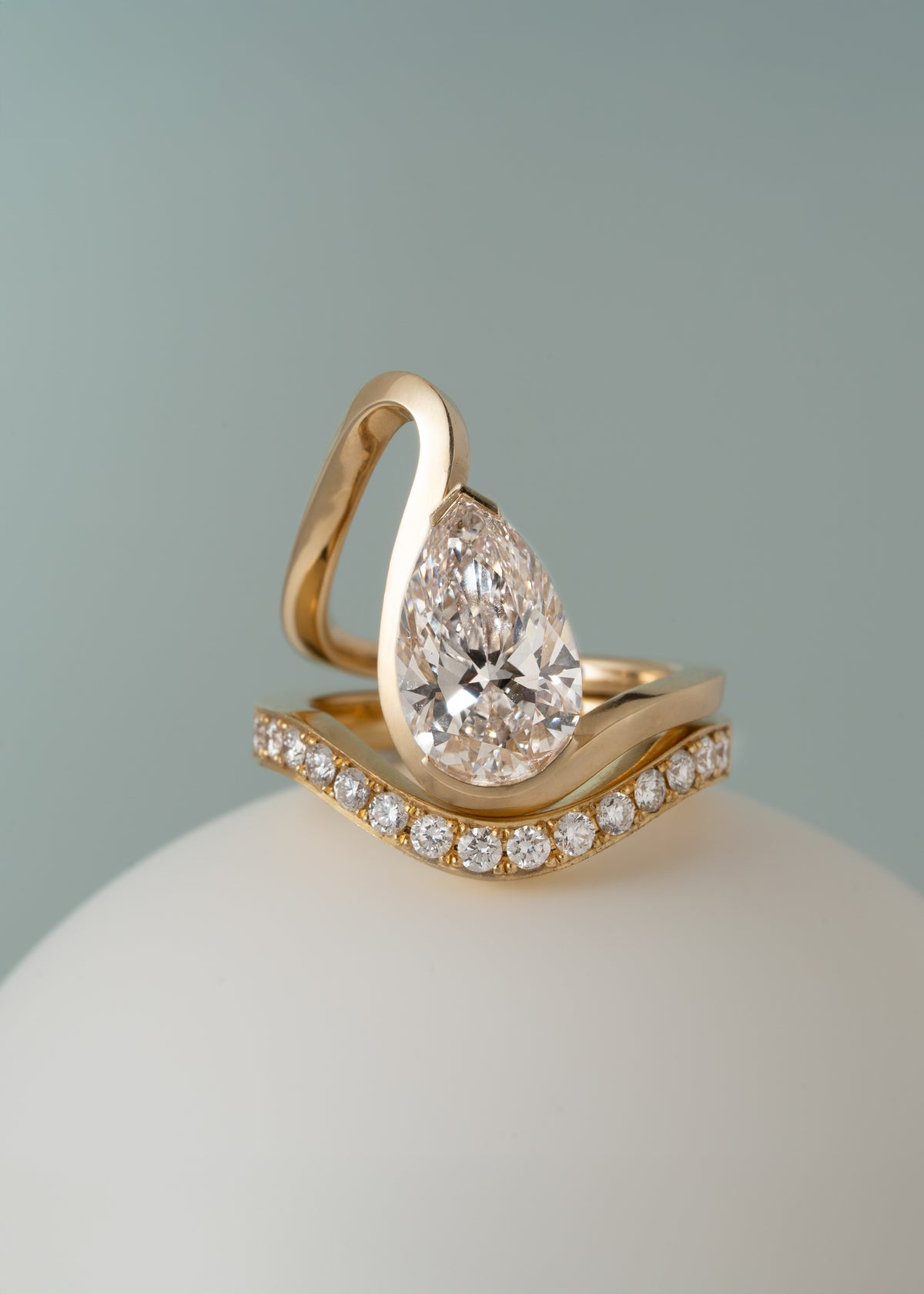 A gold wave band with a pear cut diamond paired with a wave band of pavé diamonds-18K yellow gold