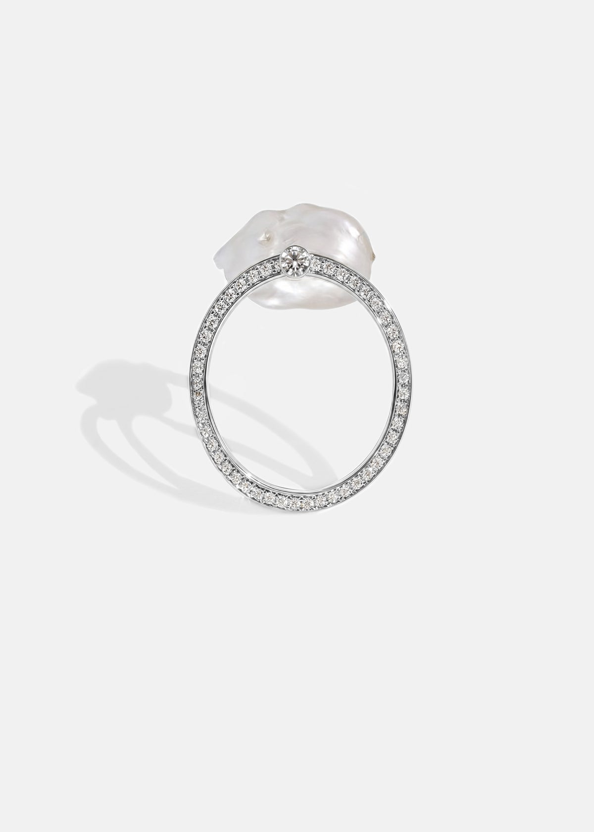 18k white gold architectural ring with a cultured freshwater pearl floating inside a circular open gold frame of pavé diamonds.
