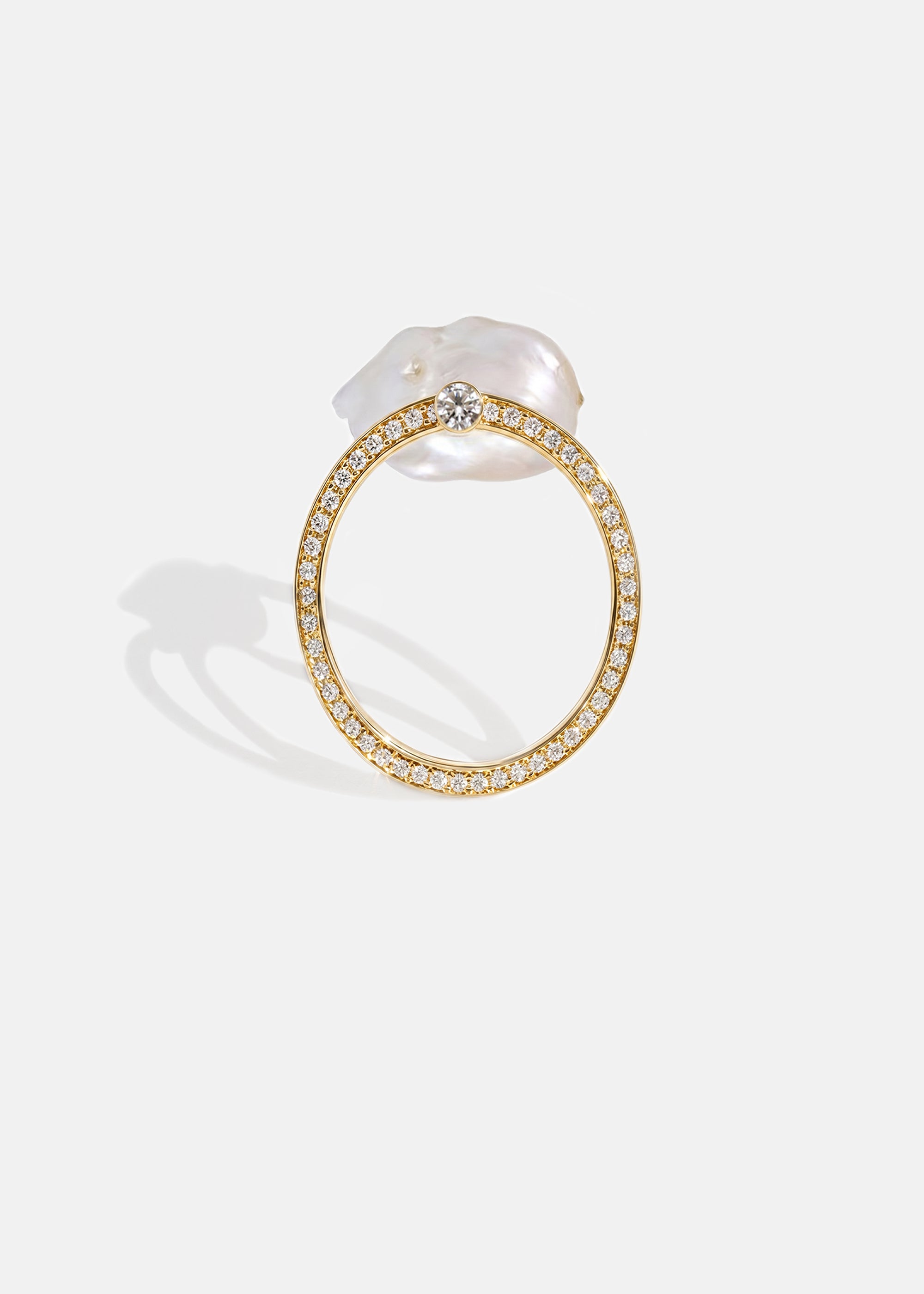 18k yellow gold architectural ring with a cultured freshwater pearl floating inside a circular open gold frame of pavé diamonds.