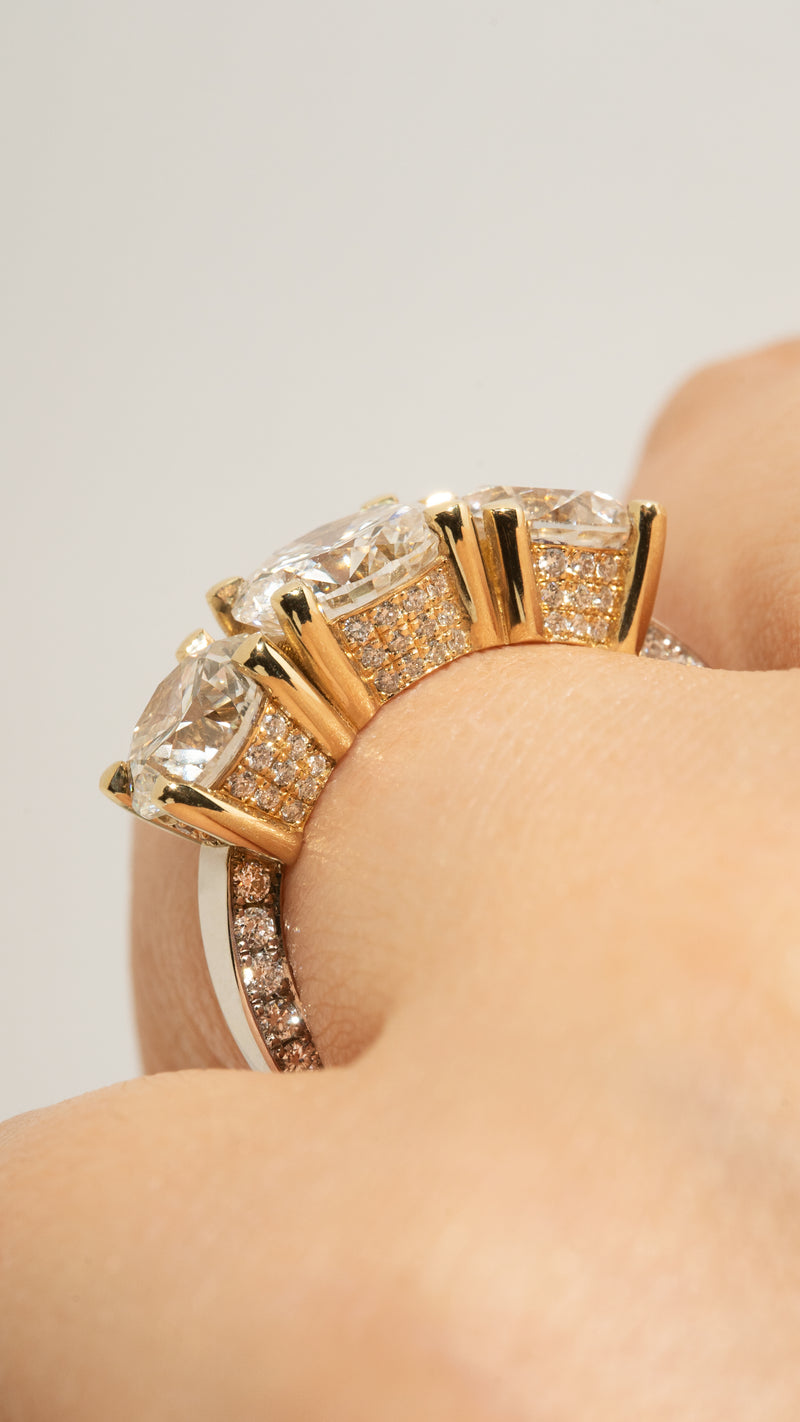 close-up of a hand wearing thin 18k white gold band with three round cut diamonds with halo pave diamonds.