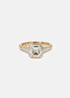 A 18k yellow gold ring featuring a central asscher-cut diamond flanked by two baguette-cut side stones
