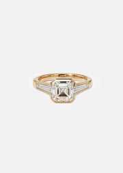A 18k yellow gold ring featuring a central asscher-cut diamond flanked by two baguette-cut side stones
