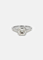 A 18k white gold ring featuring a central asscher-cut diamond flanked by two baguette-cut side stones