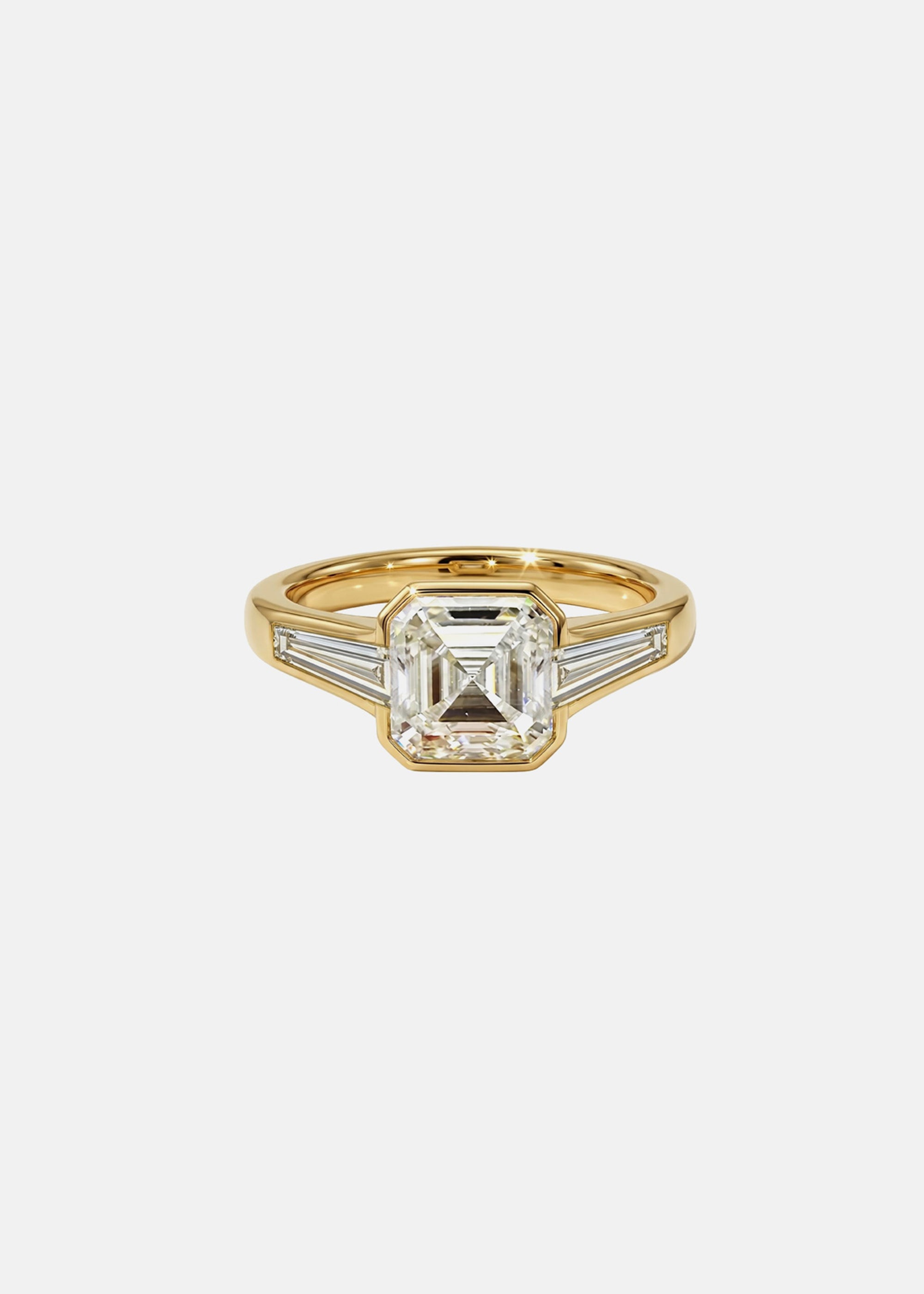 A 18k yellow gold ring featuring a central asscher-cut diamond flanked by two baguette-cut side stones