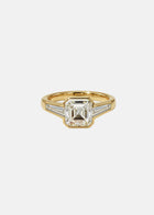 A 18k yellow gold ring featuring a central asscher-cut diamond flanked by two baguette-cut side stones