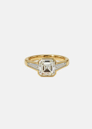 A 18k yellow gold ring featuring a central asscher-cut diamond flanked by two baguette-cut side stones