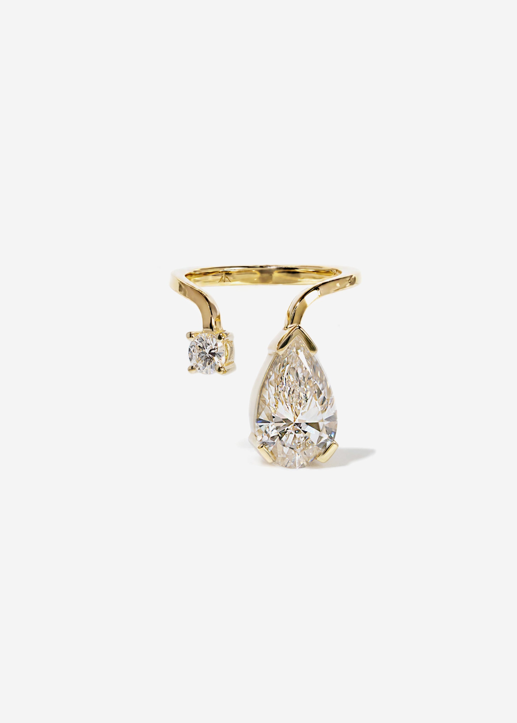 A 18k yellow gold ring featuring a large pear-cut diamond drop and a smaller round diamond accent on a curved band.