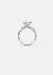 A 18k white gold solitaire engagement ring featuring a oval cut diamond  accented by small pavé diamonds on the x-shaped shank.