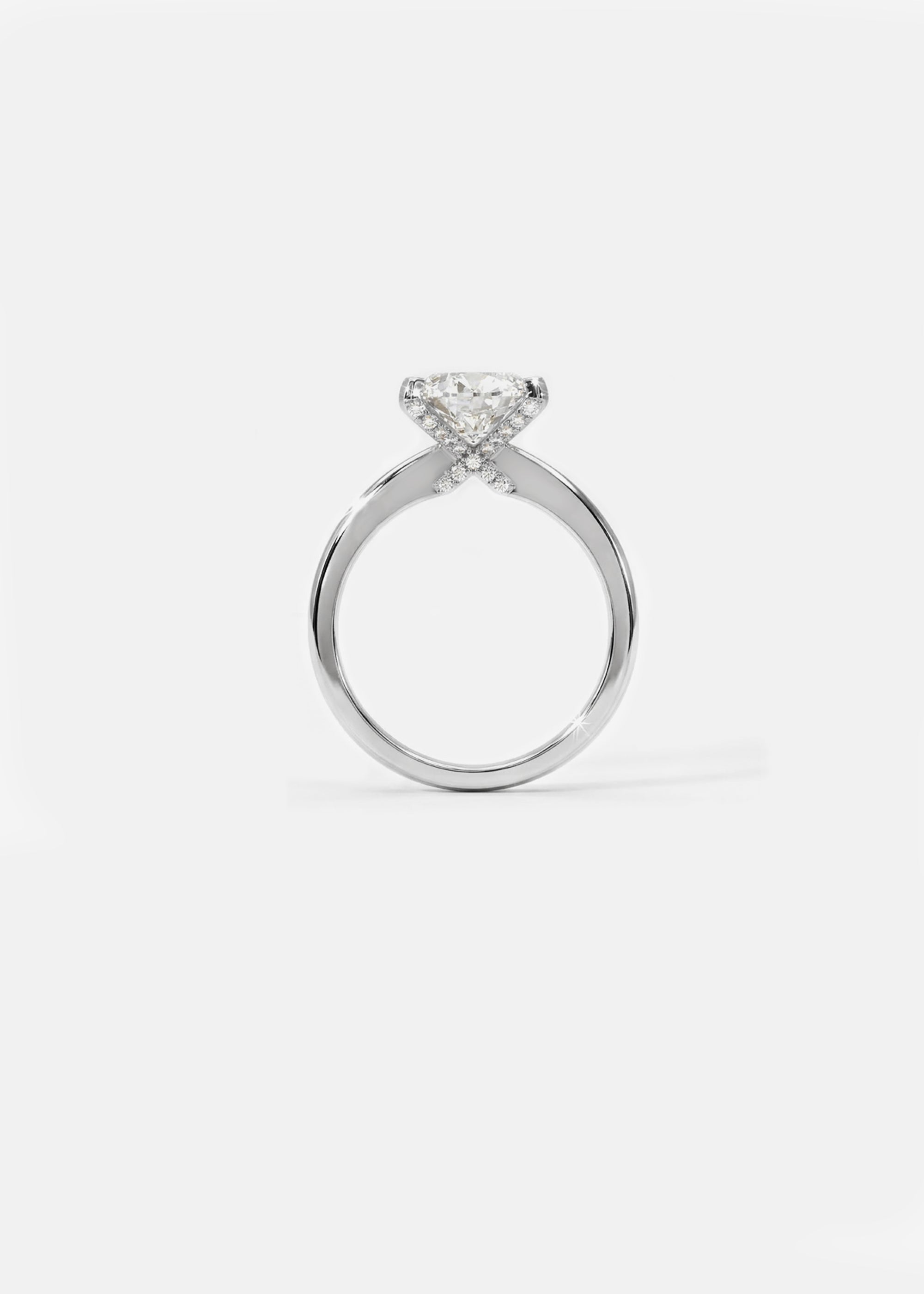 A 18k white gold solitaire engagement ring featuring a oval cut diamond  accented by small pavé diamonds on the x-shaped shank.