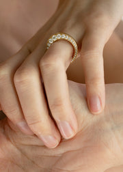 Close-up of a hand wearing a 18k yellow gold band with tapering diamonds.
