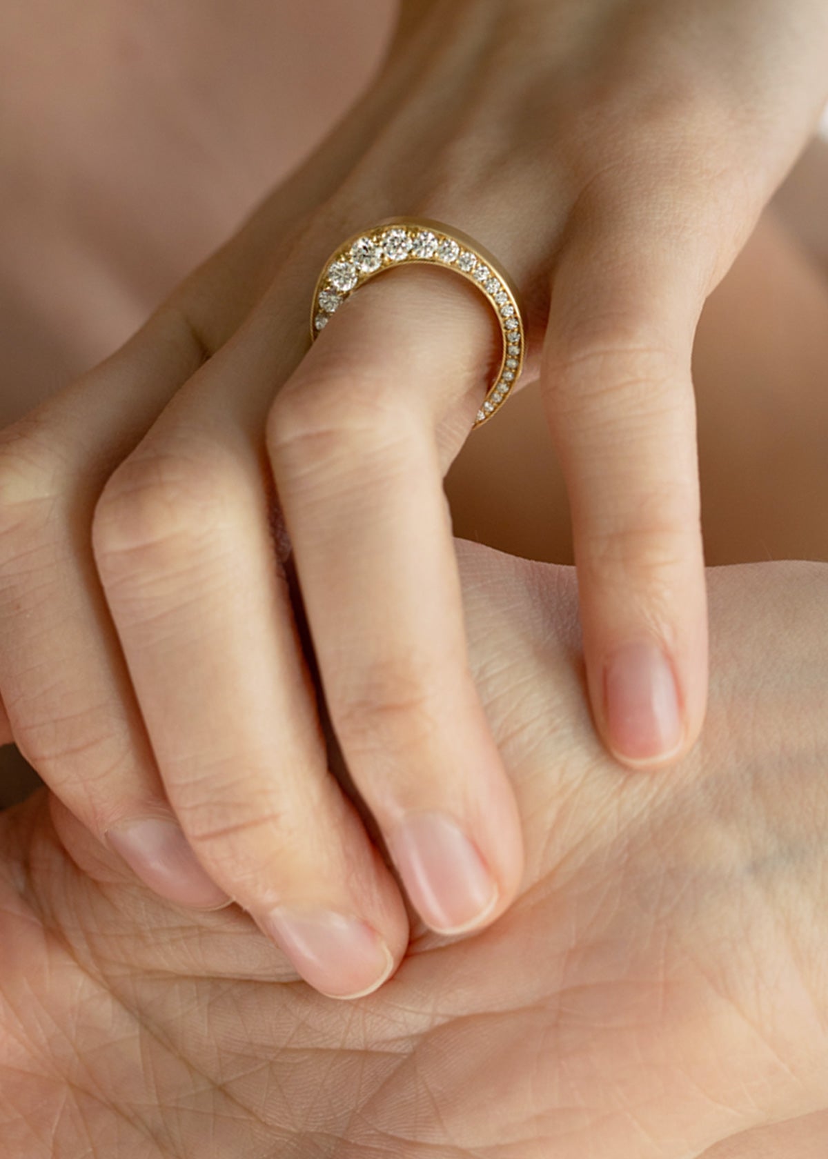 Close-up of a hand wearing a 18k yellow gold band with tapering diamonds.
