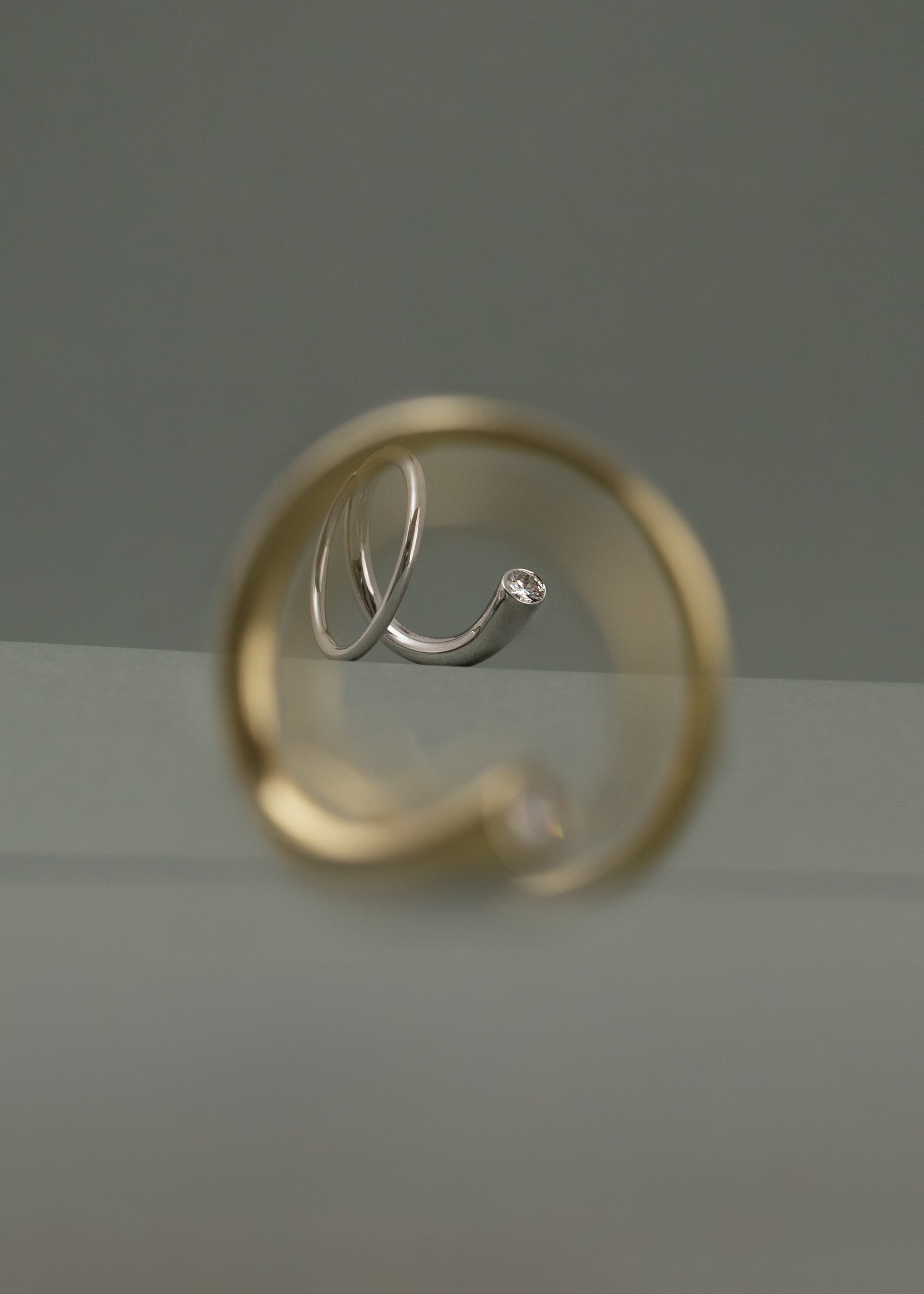 yellow gold crescendo ring in the blurry foreground and a white gold crescendo ring in focus in depth