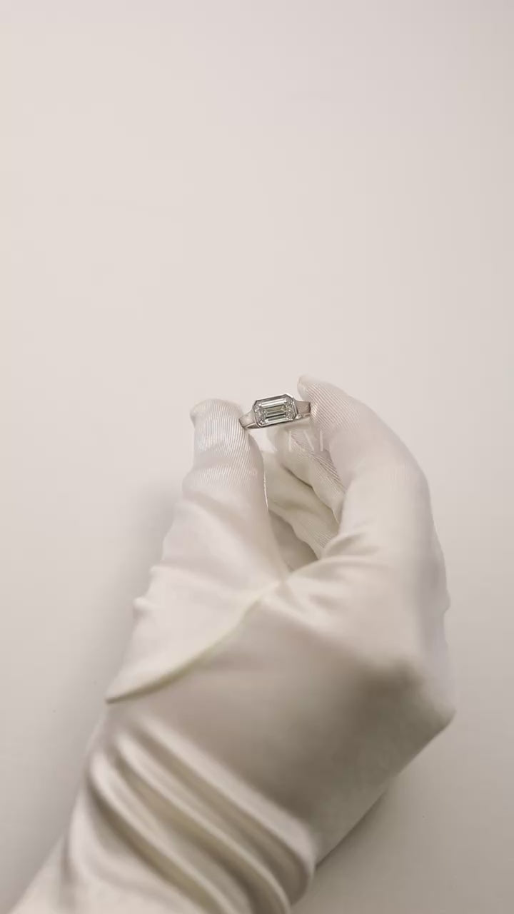 video showcasing a 18k white gold ring with a east west emerald cut diamond as the center stone