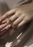 model wearing a deconstructed ring stack of 3 rings, center ring featuring 18k yellow gold architectural engagement ring with a round cut diamond in a thick, octagon bezel setting.