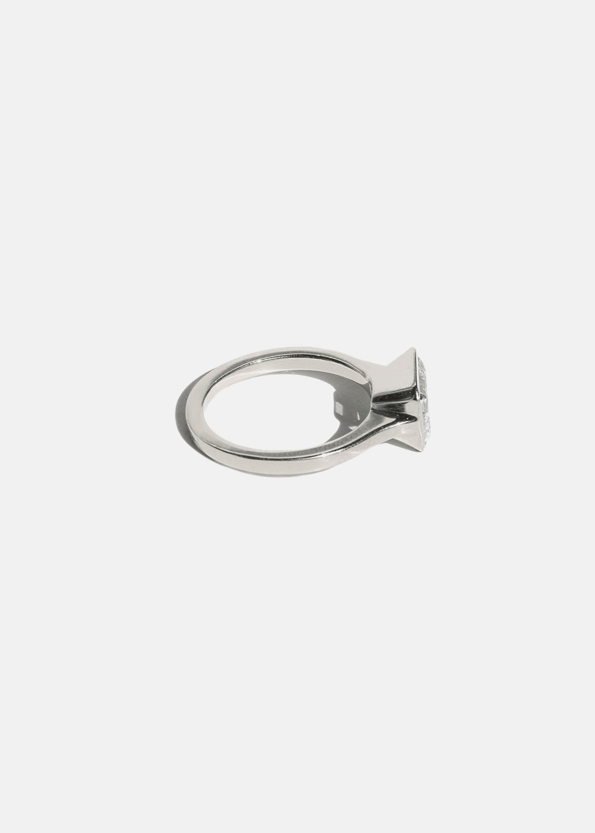 side view of a 18k white gold ring with a east west emerald cut diamond as the center stone