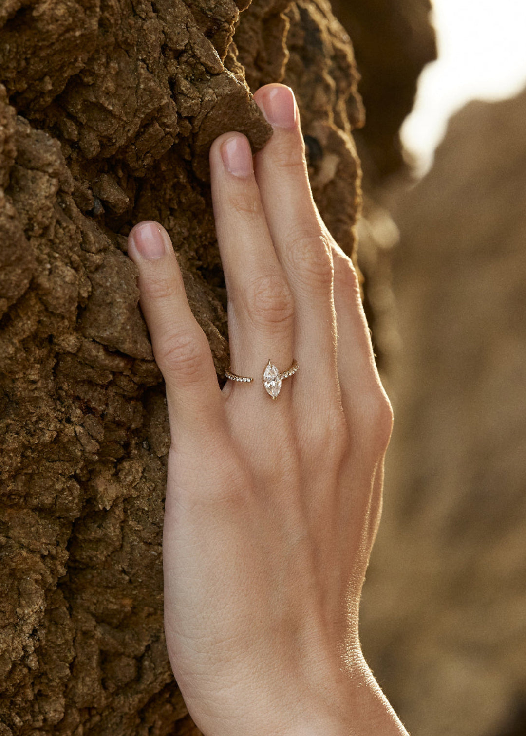 model wearing 18k yellow gold engagement ring with a floating marquise cut diamond anchored on a tapering micropavé diamond band